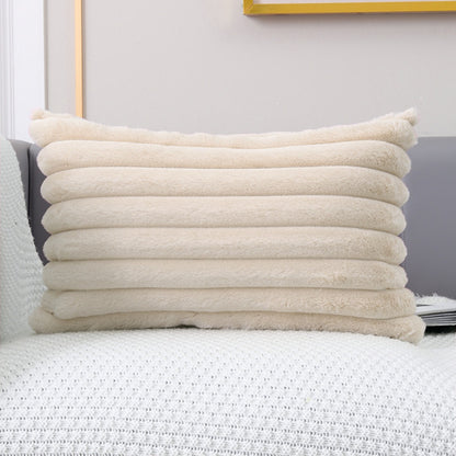 Een stapel van vijf Headrest Easing Pillow-kussens van Act Design Shop op een witte bank, met een grijze muur en een vleugje geel frame op de achtergrond.